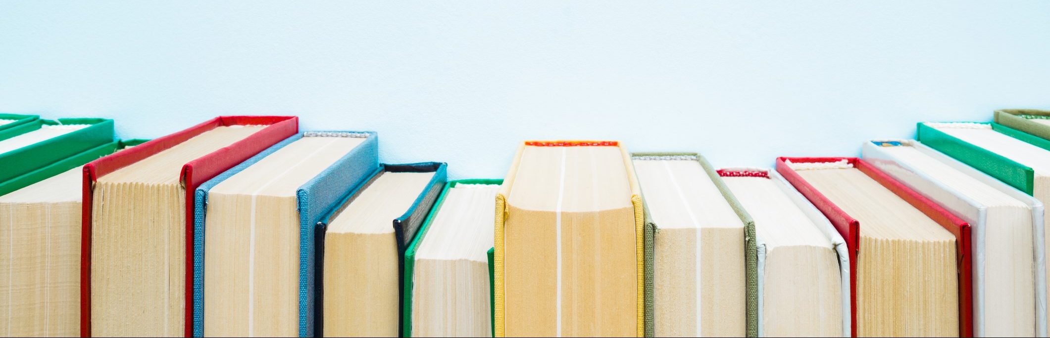 Row of old books with colorful covers on pastel blue background